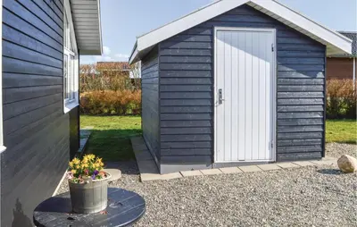 a blue shed with a white door next to a house at Holiday Home Astersvej in Lemvig
