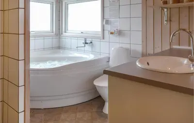 a bathroom with a tub and a toilet and a sink at Holiday Home Skovstjernevej Lemvig Ii in Lemvig