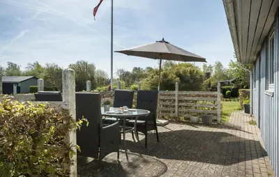 a patio with a table and an umbrella at Holiday Home Sommerstedvej Denm in Vinderup
