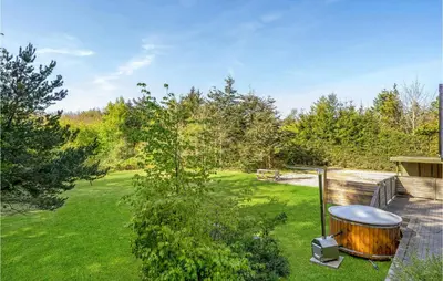 a garden with a wooden tub in the grass at Holiday Home Skibstedvej Hurup Thy in Sønder Ydby