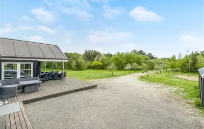 an outdoor deck with chairs and a house at Holiday Home Skovvej Thyholm Xii in Thyholm