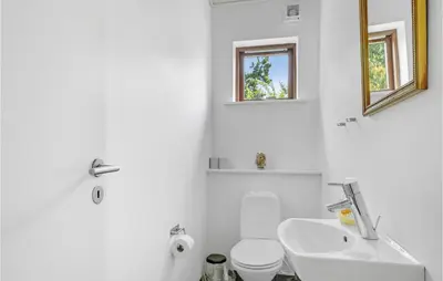 a white bathroom with a toilet and a sink at Holiday Home Skovvej Thyholm Xii in Thyholm
