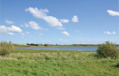 a large body of water with a green field and a blue sky at Holiday Home Kalkstensvej in Spottrup