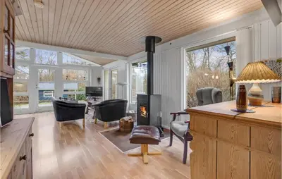 a living room with a fireplace and a table and chairs at Holiday Home Hærvej Thyholm Xi in Thyholm