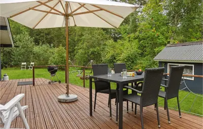a table and chairs with an umbrella on a deck at Holiday Home Hærvej Thyholm Xi in Thyholm