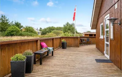 a wooden deck with a bench and a table at Lovely Home In Thyholm With Sauna in Thyholm