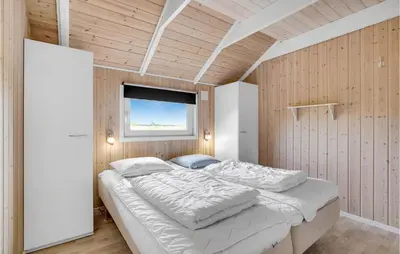 a bedroom with a large bed with a window at Lovely Home In Thyholm With Sauna in Thyholm