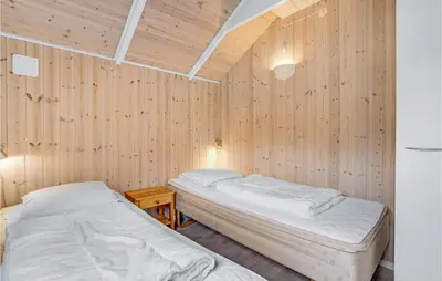 two beds in a room with wooden walls at Lovely Home In Thyholm With Sauna in Thyholm