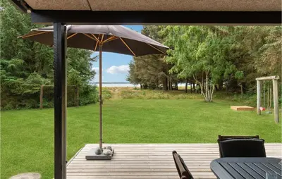 a wooden deck with an umbrella on top of it at Strandbo in Thyholm