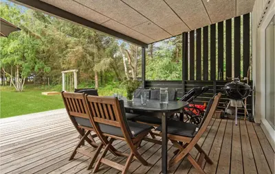 a patio with a table and chairs on a deck at Strandbo in Thyholm