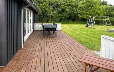 a wooden deck with a picnic table and a playground at Holiday Home Strandlyst Vinderup I in Vinderup
