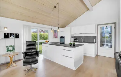 a kitchen with white cabinets and a black chair at Holiday Home Kildebakken Vinderup V in Vinderup
