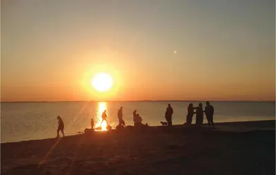 a group of people standing on the beach at sunset at Holiday Home Lærkevej Vinderup Xii in Vinderup