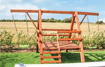 a wooden swing seat in a field of grass at Holiday Home Houmøllevej in Karby