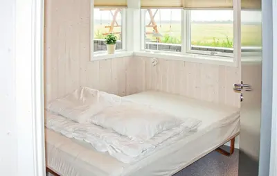 a bed sitting in a room with two windows at Holiday Home Houmøllevej in Karby