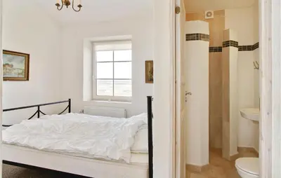 a white bedroom with a bed and a bathroom at Bakkegården in Vesløs