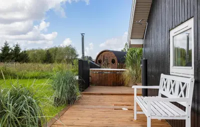 a wooden deck with a white bench on a house at Holiday Home Ballesvej in Øster Assels