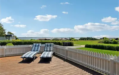 two blue chairs sitting on a deck with a fence at Holiday Home Limfjordsvangen Snedsted X in Snedsted