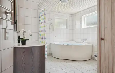 a white bathroom with a tub and a sink at Holiday Home Limfjordsvangen Snedsted X in Snedsted