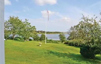 a kite flying in a field next to a lake at Holiday Home Følvigvej Roslev I in Roslev
