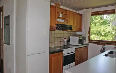 a kitchen with wooden cabinets and a white refrigerator at Holiday Home Kraghøjvej Nykøbing M Ix in Hesselbjerg