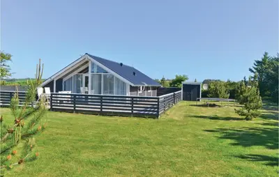 a house with a fence and a grass yard at Holiday Home Sulevej Hurup Thy Xi in Sindrup