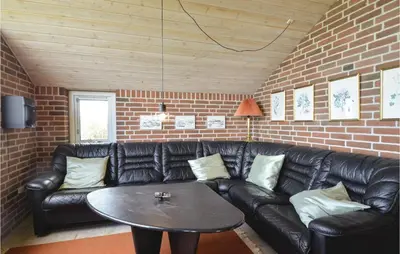 a black leather couch in a living room with a table at Holiday Home Grynderup Strand Roslev in Roslev