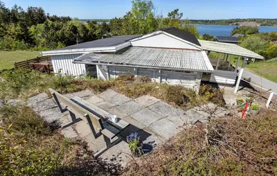 a building on a hill with a bench in front of it at Holiday Home Pinen Roslev X in Roslev