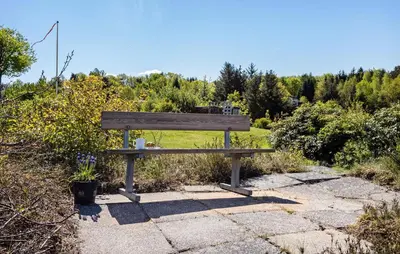 a wooden bench sitting on a sidewalk in a park at Holiday Home Pinen Roslev X in Roslev