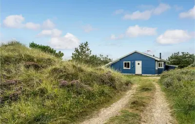 a blue house on a hill next to a dirt road at Holiday Home Svenstibakkevej Ii in Frøstrup