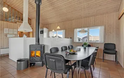 a dining room with a table and a wood stove at Stunning Home In Thisted With Sauna in Klitmøller