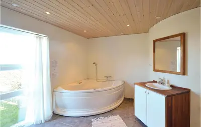 a bathroom with a tub and a sink and a mirror at Holiday Home Glombak in Vesløs