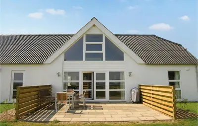 a white house with a table and chairs in front of it at Holiday Home Glombak in Vesløs