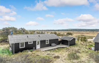 a black house sitting on top of a field at Holiday Home Johnsvej Thisted V in Thisted