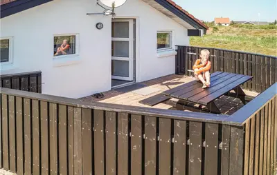 a small child sitting on a picnic table on a deck at Amazing Home In Thisted With Sauna in Thisted