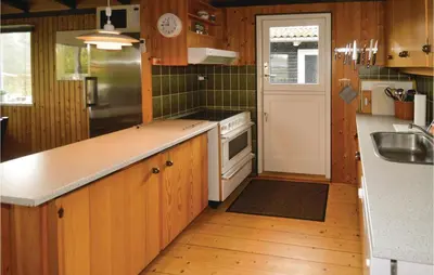a kitchen with wooden cabinets and a stove top oven at Holiday Home Fjordparken Farsø Iv in Farsø