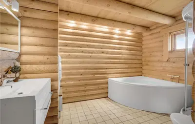 a bathroom with a white tub and wooden walls at Holiday Home Husvej in Fur