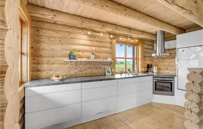a kitchen with white cabinets and a wooden wall at Holiday Home Husvej in Fur