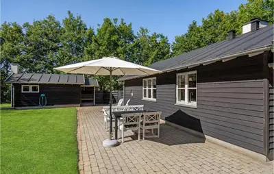 a patio with a table and an umbrella at Holiday Home Furvej in Vesløs