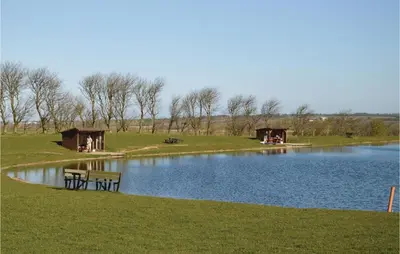 a lake with a couple of tables and chairs next to it at Holiday Home Hellesvej Løgstør Xi in Løgstør