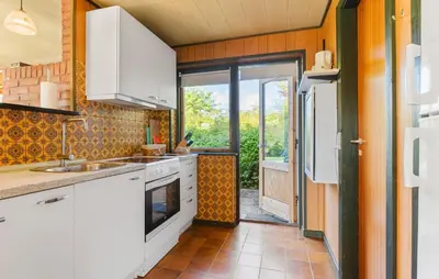 a kitchen with white cabinets and an open door at Holiday Home Bjarkesvej in Farsø