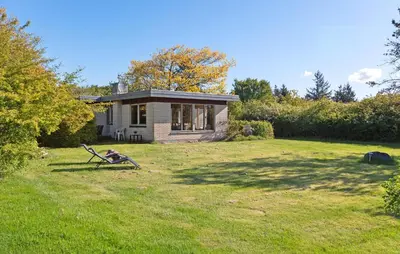 a small house in a yard with a grassy field at Holiday Home Bjarkesvej in Farsø