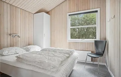 a bedroom with a bed and a chair and a window at Holiday Home Revlingestien Fjerritslev V in Fjerritslev
