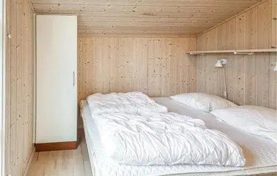 a bed in a room with a wooden wall at Holiday Home Revlingestien Fjerritslev Iv in Fjerritslev