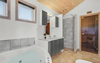 a bathroom with a tub and a sink and a shower at Holiday Home Svenstibakkevej Denmark I in Frøstrup
