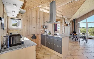 a kitchen with wood paneling and a counter with a sink at Holiday Home Svenstibakkevej Denmark I in Frøstrup