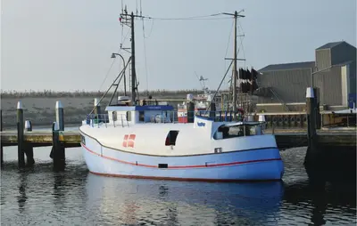 a boat sitting in the water next to a dock at Holiday Home Hjelmevej Ulfborg Vi in Ulfborg