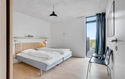a bedroom with two beds and a chair at Holiday Home Hjelmevej Ulfborg Vi in Ulfborg