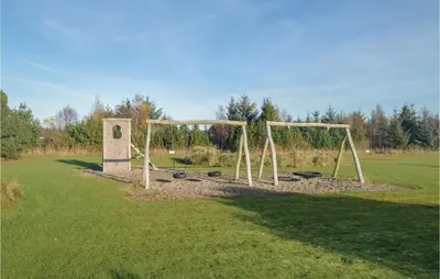 a park with two swings in a grass field at 4 Bedroom Cozy Home In Brovst in Brovst