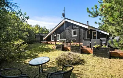 a black house with chairs and a table in the yard at 4 Bedroom Cozy Home In Brovst in Brovst